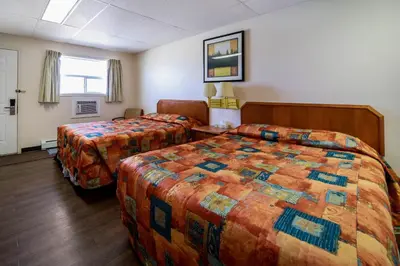 a hotel room with two beds and a window at Canadas Best Value Inn Fort St John in Fort Saint John