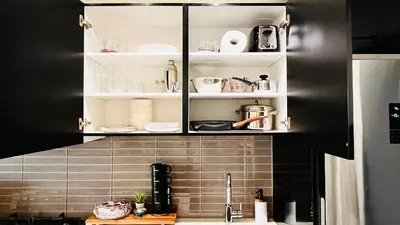 a kitchen with black and white cabinets with dishes at LUXURY Downtown Sunset Getaway - Your Home Away From Home - Fully Stocked Kitchen, Gym, Balcony, FREE PARKING in Calgary