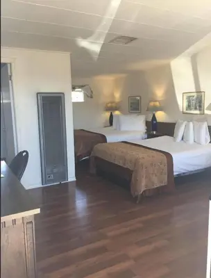 a hotel room with two beds and wooden floors at Robbie's Motel in Cache Creek