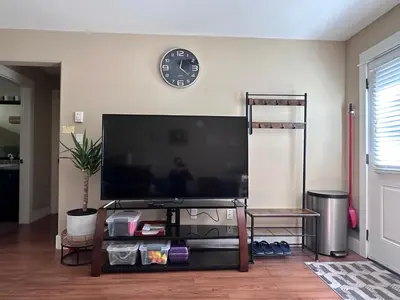 a large flat screen tv on a wall with a clock at Separate entry sweet home in Victoria