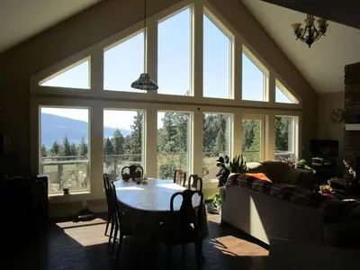 a living room with a table and a large window at Okanagan Lake Sunrise BB in Vernon