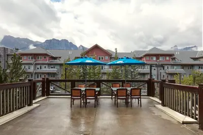 a balcony with tables and chairs with blue umbrellas at Spacious King Bed with Pool & Hot Tubs in Canmore
