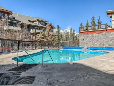 a swimming pool with blue water in a yard at Spacious King Bed with Pool & Hot Tubs in Canmore