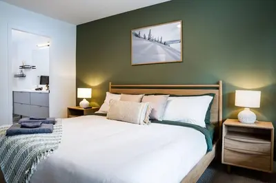 a bedroom with a large white bed with two lamps at Revy Bliss - Dazzling Condo in the Mountains in Revelstoke