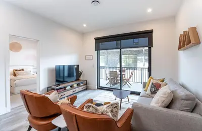 a living room with a couch and chairs and a tv at Summit Place - Condo With Mountain Views in Revelstoke