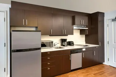 a kitchen with brown cabinets and a stainless steel refrigerator at TownePlace Suites by Marriott Red Deer in Red Deer