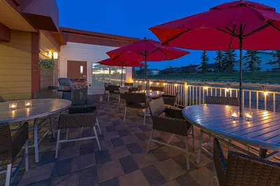a patio with tables and chairs and red umbrellas at TownePlace Suites by Marriott Red Deer in Red Deer