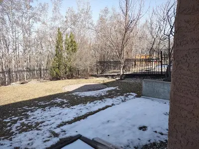 a yard covered in snow in front of a fence at Spacious One Bedroom Walkout Basement Suite in Calgary