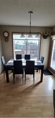 a dining room table with chairs and a large window at Spacious comfortable Air-Conditioned. Near airport! in Calgary