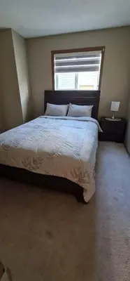 a bedroom with a large bed with a window at Spacious comfortable Air-Conditioned. Near airport! in Calgary