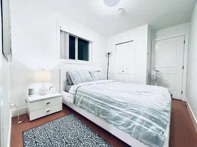 a white bedroom with a bed and a window at Charming 1BR near Metrotown DT Burnaby/ Vancouver in Vancouver
