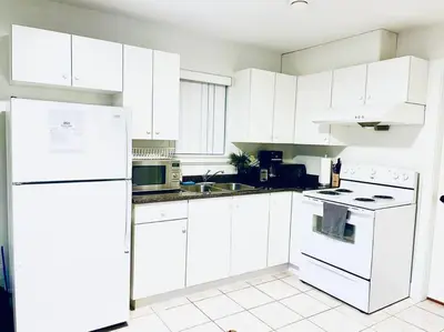 a white kitchen with white appliances and white cabinets at Charming 1BR near Metrotown DT Burnaby/ Vancouver in Vancouver