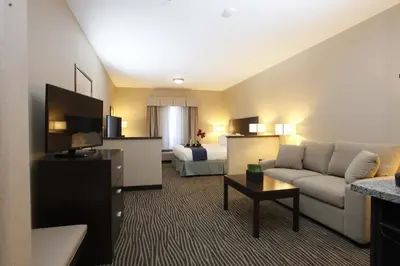 a living room with a couch and a room with a bed at Holiday Inn Express Fort St John by IHG in Fort Saint John