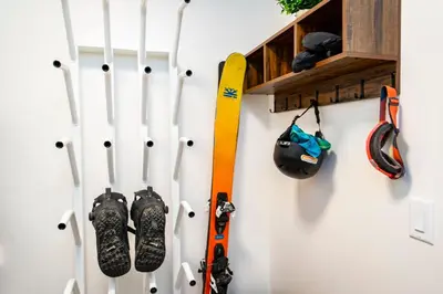 a group of skis and ski poles hanging on a wall at The Shred Shack - Stylish Revelstoke Condo in Revelstoke