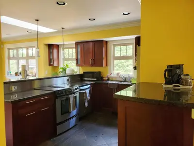 a kitchen with yellow walls and wooden cabinets at Elegant, Sunny Modern Home with Skylights - Kitsilano, Vancouver in Vancouver
