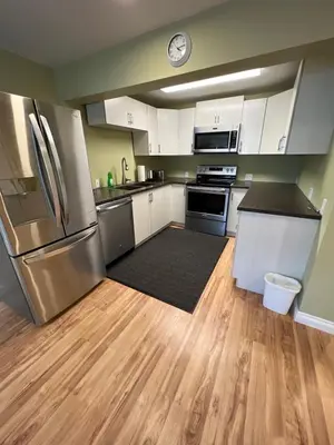 a kitchen with white cabinets and stainless steel appliances at Bluejay Suites B&B in Whitehorse