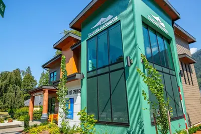 a house with a green exterior at Wanderlust Studio Suite with Private Patio in Harrison Hot Springs