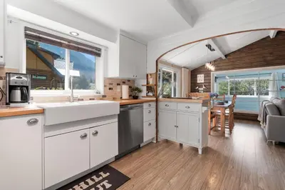 a kitchen with white cabinets and a large window at Lake Time Harrison in Harrison Hot Springs