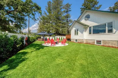 a yard with red chairs and a gazebo at Backyard Oasis Hot Tub, BBQ, Outdoor Bar in Invermere