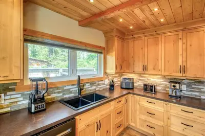 a kitchen with wooden cabinets and a sink and a window at Backyard Oasis Hot Tub, BBQ, Outdoor Bar in Invermere