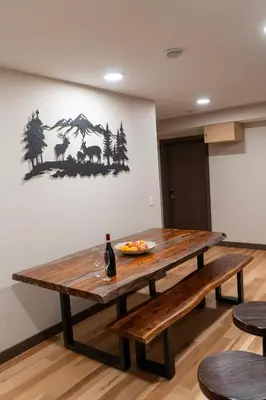 a wooden table with a bowl of fruit and a bottle of wine at Romantic Luxury Retreat with Private Sauna & Spa, Pet Friendly, Elkside Hideout B&B in Canmore