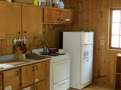 a kitchen with a stove and a white refrigerator at HI Rampart Creek - Hostel in Saskatchewan River Crossing