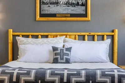 a bed with white pillows and a picture on the wall at Brewster Mountain Lodge in Banff