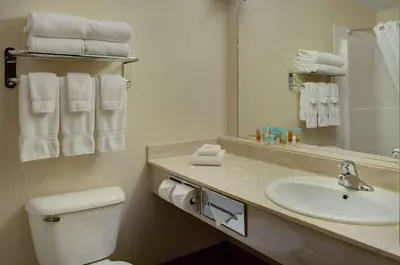 a bathroom with a sink and a toilet and a mirror at Coast Grimshaw Hotel & Suites in Grimshaw