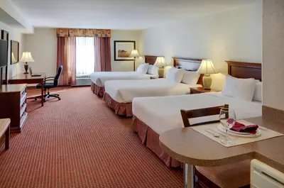 a hotel room with two beds and a table with wine glasses at Coast Grimshaw Hotel & Suites in Grimshaw