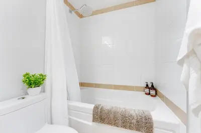 a white bathroom with a tub and a toilet at Heart of Downtown 1 bd Entire Condo - Pool, Gym, Parking, Office, AC in Vancouver