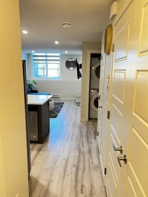 an open door to a laundry room with a washer and dryer at The Waterfront cozy 1 bd suite in Rockland Park, Tuscany NW in Calgary