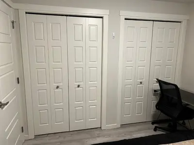 two white doors in a room with a chair at The Waterfront cozy 1 bd suite in Rockland Park, Tuscany NW in Calgary