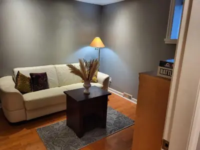 a living room with a couch and a table with a lamp at Garden suite on Trinity St in Vancouver
