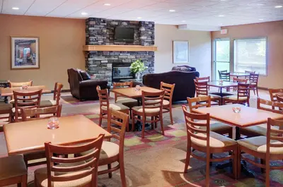 a restaurant with tables and chairs and a fireplace at Pomeroy Inn and Suites Dawson Creek in Dawson Creek