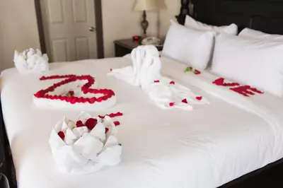 a white bed with red and white decorations on it at Pomeroy Inn and Suites Dawson Creek in Dawson Creek