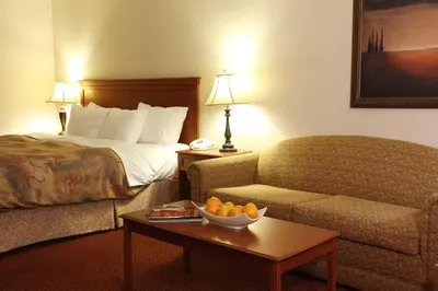 a hotel room with a bed and a table with a bowl of fruit at Pomeroy Inn and Suites Dawson Creek in Dawson Creek