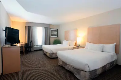 a hotel room with two beds and a flat screen tv at Pomeroy Inn and Suites Dawson Creek in Dawson Creek