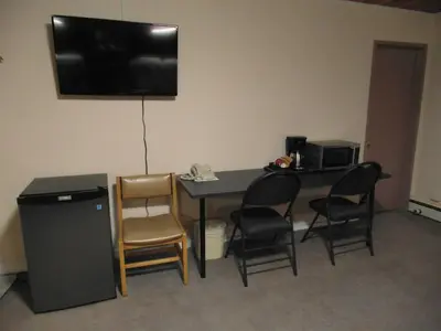 a room with a table and chairs and a television at West View Motel in Hanna