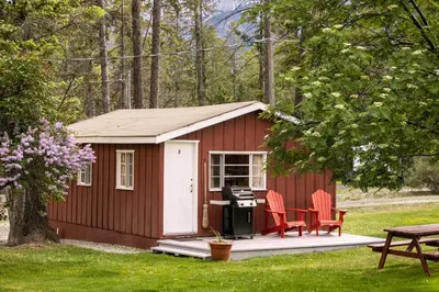 a red shed with two chairs and a grill at Timbers Resort in Fairmont Hot Springs