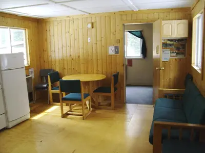 a room with a table and chairs and a refrigerator at HI Mosquito Creek - Wilderness Hostel in Lake Louise