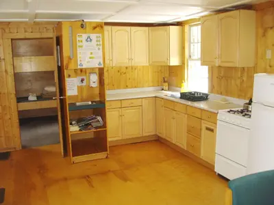 a kitchen with wooden cabinets and a white refrigerator at HI Mosquito Creek - Wilderness Hostel in Lake Louise