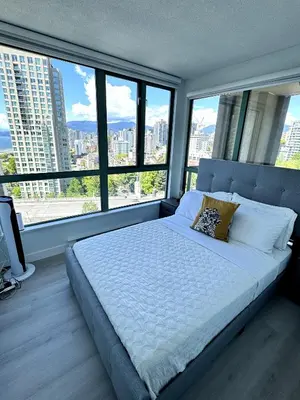 a bedroom with a large bed with large windows at Stunning ocean (sound of waves) in Vancouver