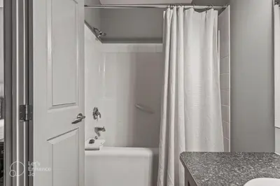 a white bathroom with a shower curtain and a toilet at Rocky Mountain Getaway with Outdoor Heated Pool, 3 Hot Tubs, Gym, BBQ, Garage & 24 hour Reception near Banff in Canmore