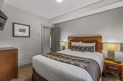 a bedroom with a large bed and two lamps at Rocky Mountain Getaway with Outdoor Heated Pool, 3 Hot Tubs, Gym, BBQ, Garage & 24 hour Reception near Banff in Canmore