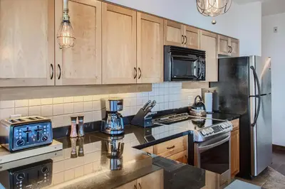 a kitchen with wooden cabinets and a stainless steel refrigerator at The Crescent 201 by Okanagan Premier in Big White