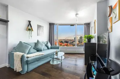 a living room with a blue couch and a large window at Downtown 1 Bedroom Water View Condo in Vancouver