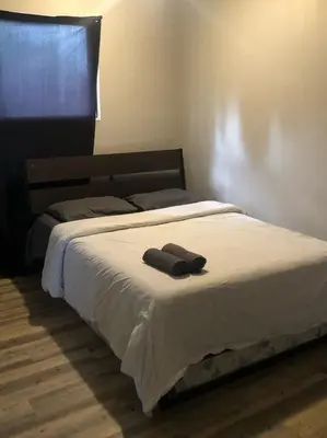 a bed with a pair of towels on top of it at Flowealth Suites - Private Rooms Near West Edmonton Mall in Edmonton