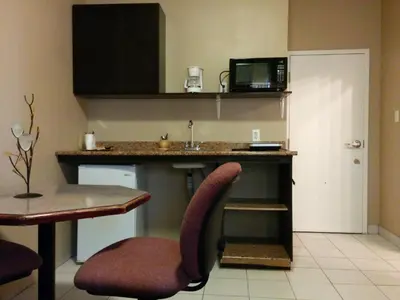 a kitchen with a sink and a table with a microwave at Bonnyville Hotel in Bonnyville