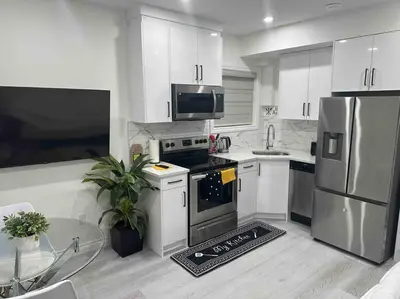 a kitchen with white cabinets and stainless steel appliances at Award winning boho paradise sunlit modern suite in Calgary