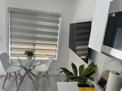 a dining room with a glass table and white chairs at Award winning boho paradise sunlit modern suite in Calgary